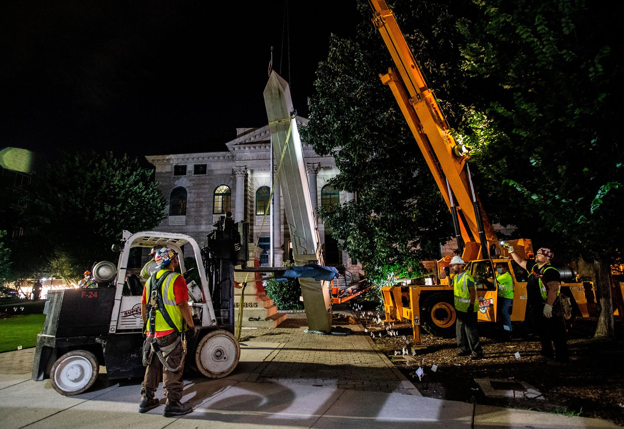 Workers remove a Confederate monument with a crane