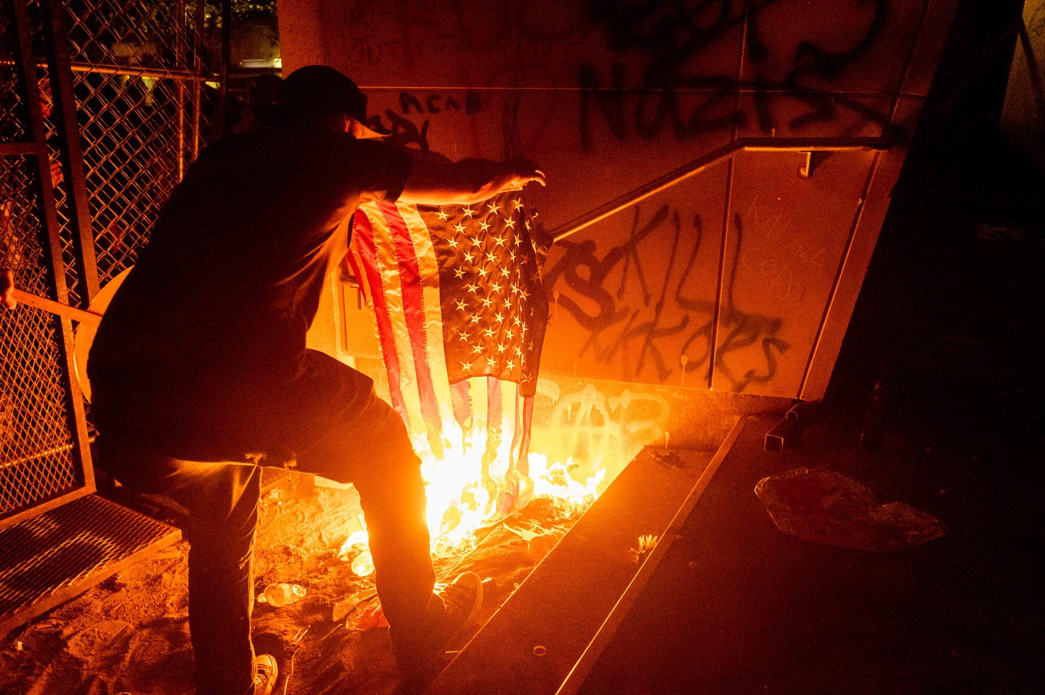 A Black Lives Matter protester burns an American flag outside the Mark O. Hatfield United States Courthouse on Monday, July 20