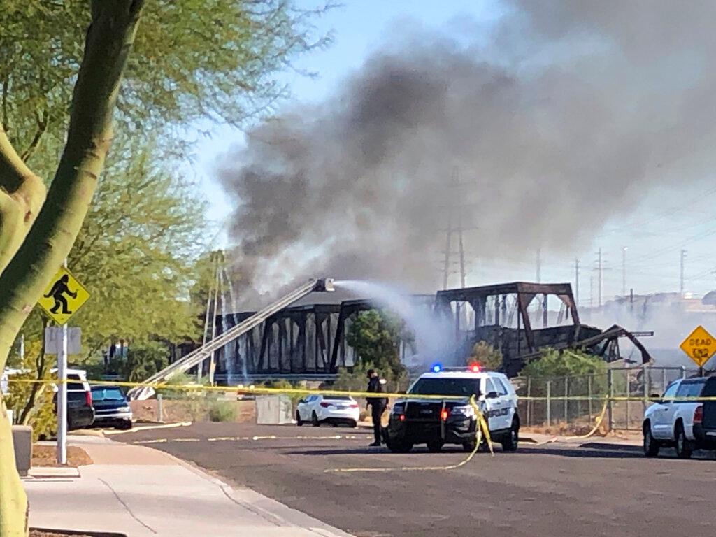 Officials say a freight train traveling on a bridge that spans a lake in the Phoenix suburb derailed and set the bridge ablaze and partially collapsing the structure.