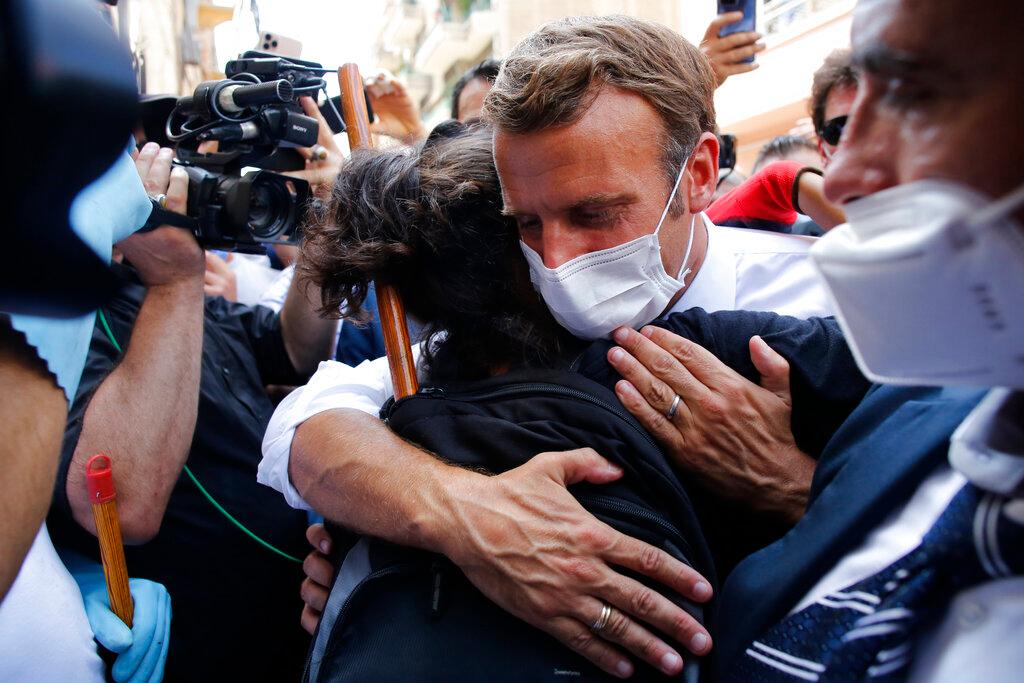 Emmanuel Macron hugs a resident as he visits a devastated street of Beirut