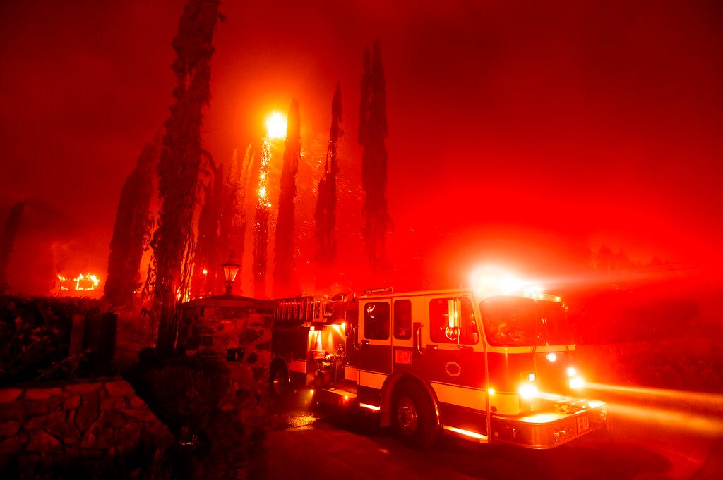 A fire engine leaves a burning property as the Glass Fire tears through St. Helena, Calif.