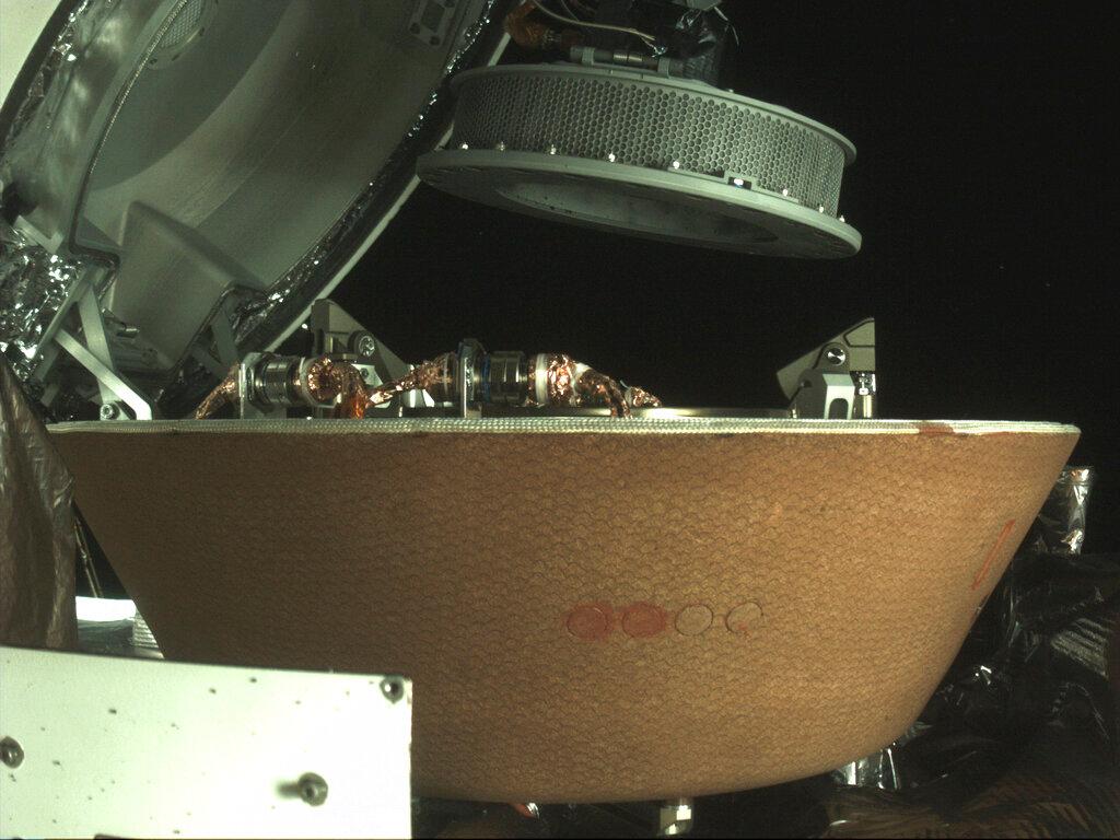 Sample container hovers over a capsule on the Osiris-Rex spacecraft near the asteroid Bennu