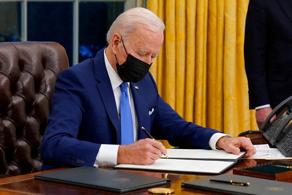 President Joe Biden signs an executive order on immigration, in the Oval Office