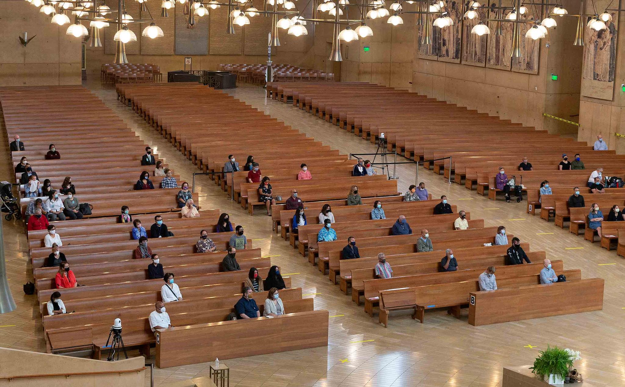 file photo, a hundred faithful sit while minding social distancing, listening to Los Angeles Archbishop Jose H. Gomez celebrate Mass at Cathedral of Our Lady of the Angels, the first Mass held in English at the site since the re-opening of churches, in downtown Los Angeles.