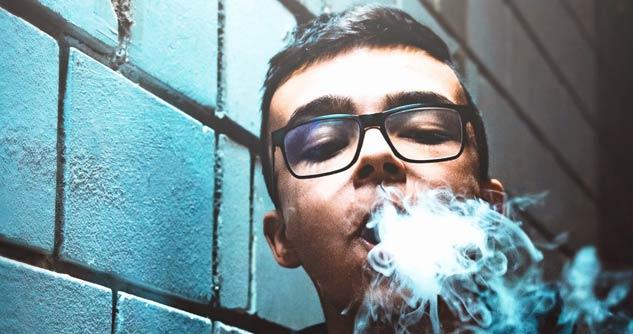 Young teen blowing out vape vapor