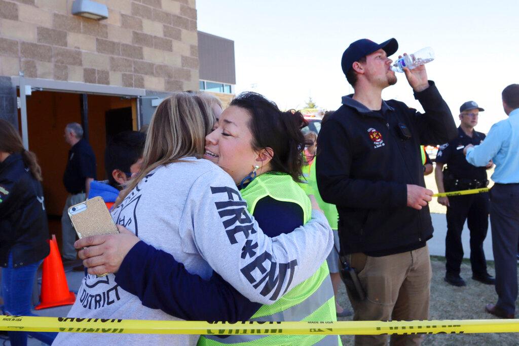 People embrace outside the high school where people were evacuated after a shooting at the nearby Rigby Middle School earlier Thursday, May 6, 2021, in Rigby, Idaho. Authorities said that two students and a custodian were injured, and a male student has been taken into custody.