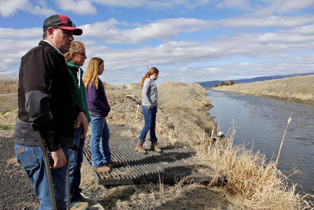 people standing near a canal for collecting run-off water