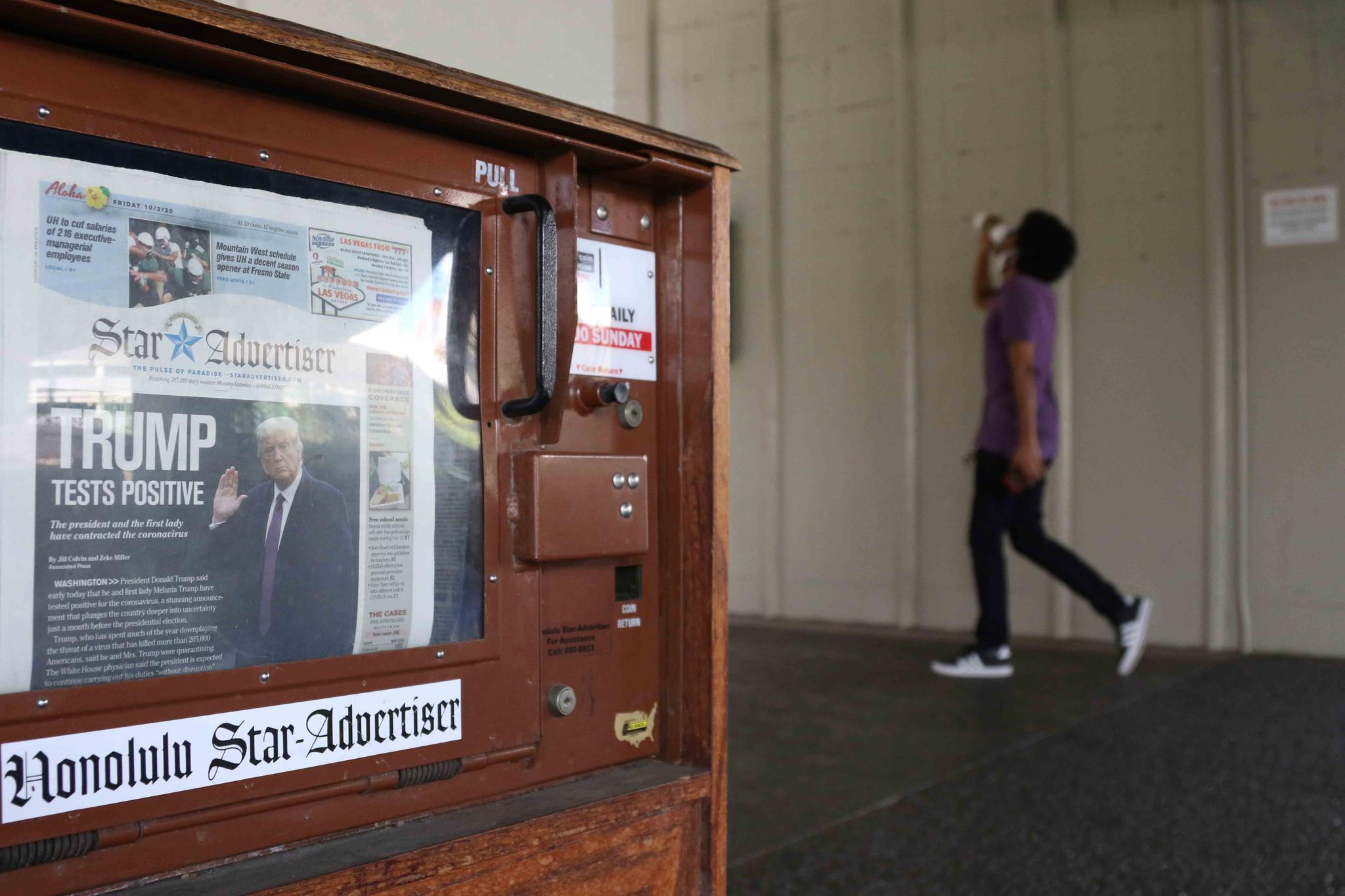 A man walks past a newspaper stand at the international airport in Honolulu on Friday, Oct. 2, 2020