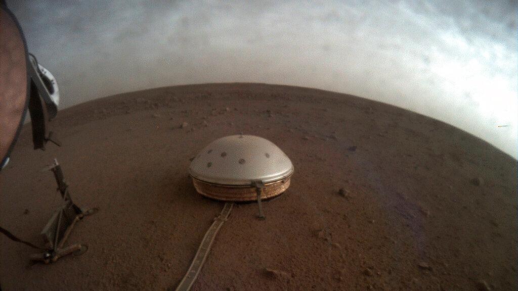 Clouds drift over dome-covered SEIS seismometer of InSight lander on surface of Mars