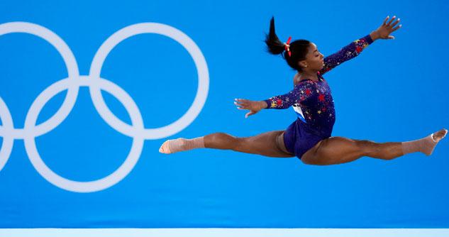 Gymnast Simone Biles mid-air in a blue leotard