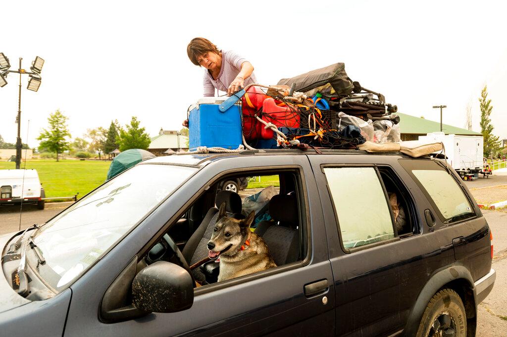 Greenville resident Kesia Studebaker, who lost her home to the Dixie Fire, secures belongings before leaving a Susanville, Calif., evacuee shelter with her dog Logan 