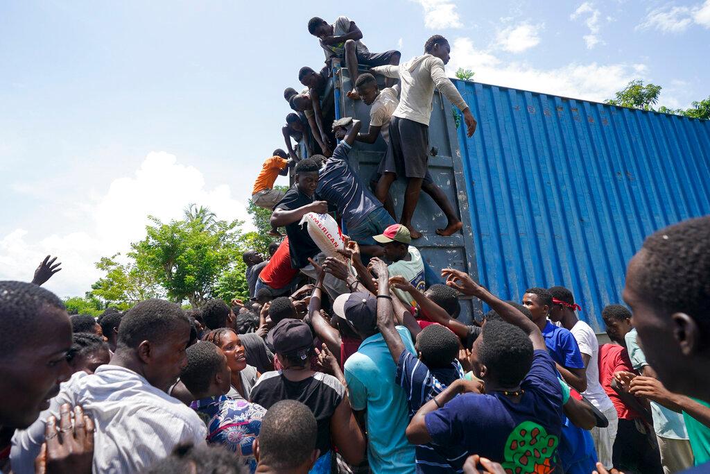 Residents overtake a truck loaded with relief supplies in Vye Terre, Haiti