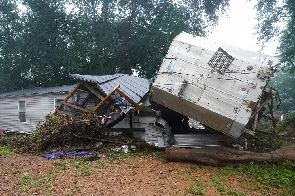 A mobile home and a truck trailer sit near a creek Sunday, Aug. 22, 2021, after they were washed away by flood waters in McEwen, Tenn.