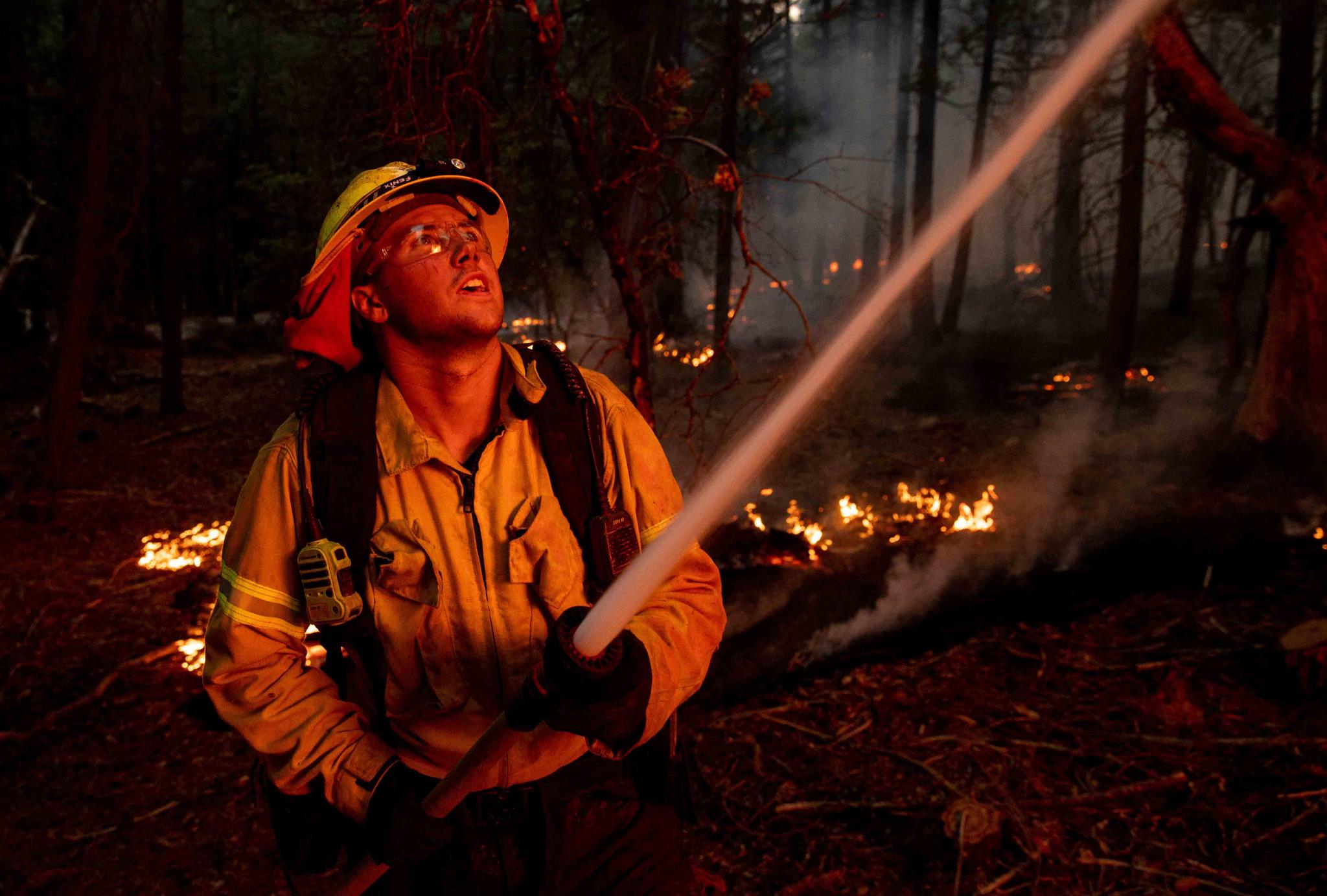 A firefighter hoses down flames from the Dixie Fire in Genesee, Calif., on Saturday, Aug. 21, 2021.