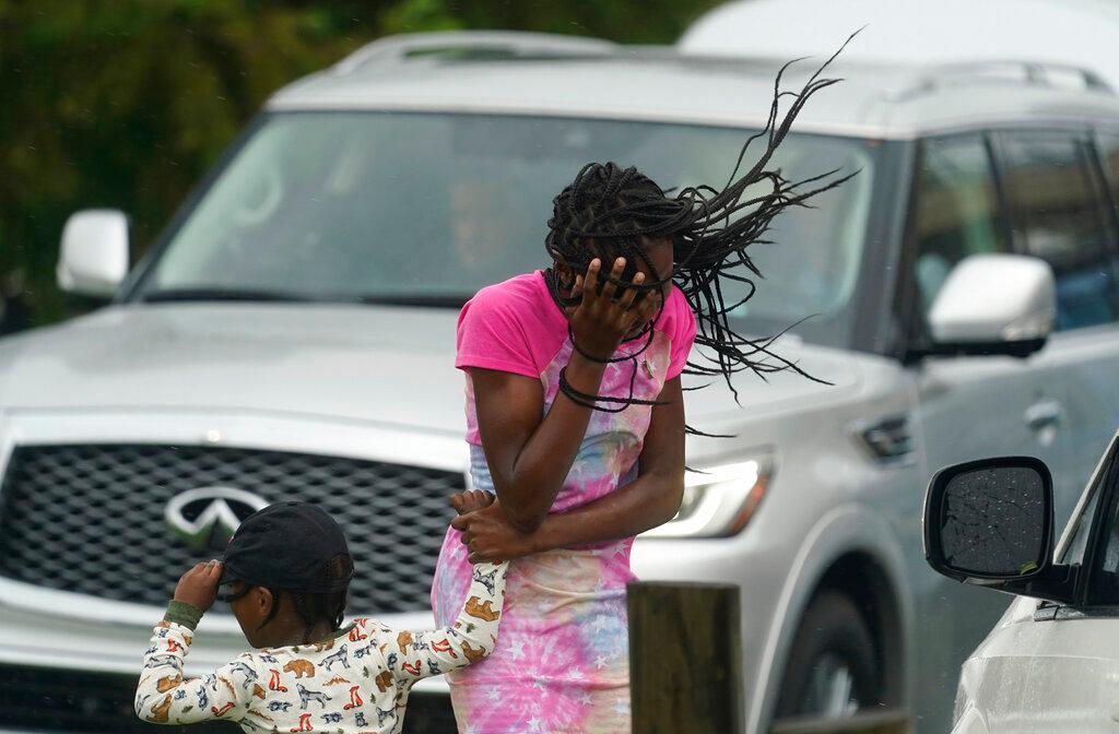 A young girl blocks her face from the wind and rain produced by Hurricane Ida,