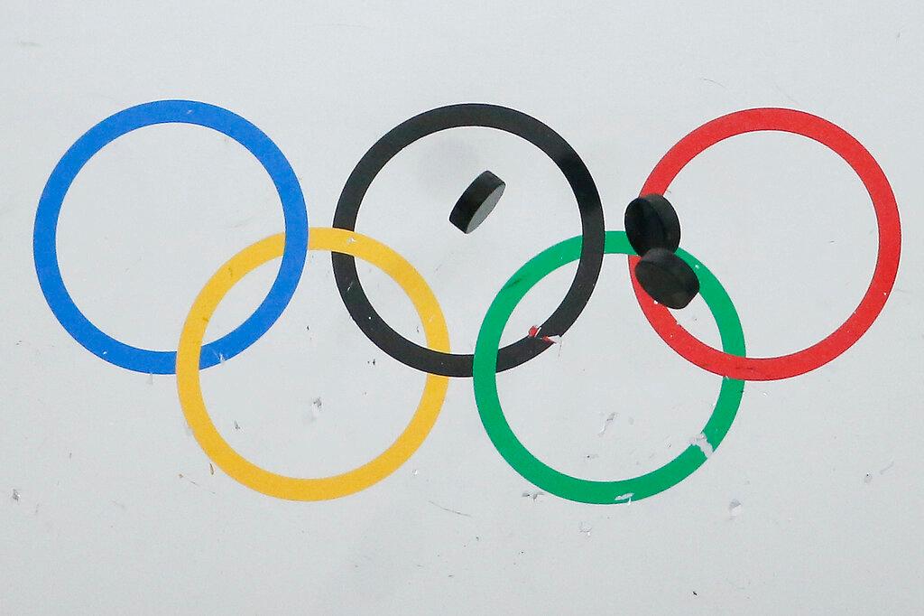 In this Feb. 22, 2014, file photo, hockey pucks bounce off the wall during the warm up session before the USA vs Finland men's bronze medal ice hockey game at the 2014 Winter Olympics in Sochi, Russia. National Hockey League players are set to return to the Olympics in Beijing this winter after reaching an agreement with international officials. The league, NHLPA, International Olympic Committee and International Ice Hockey Federation struck a deal Friday, Sept. 3, 2021, that will put the best players in the world back on sports' biggest stage in February after skipping the 2018 Winter Games in South Korea.