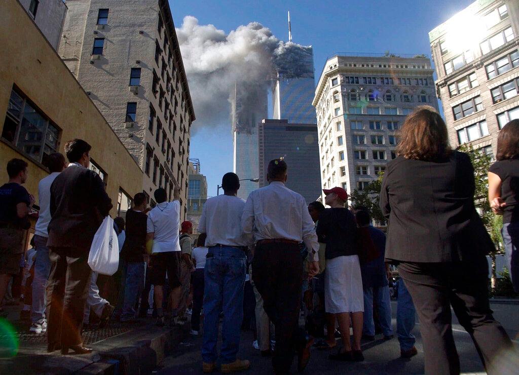 Pedestrians in lower Manhattan watch smoke billow from New York's World Trade Center 