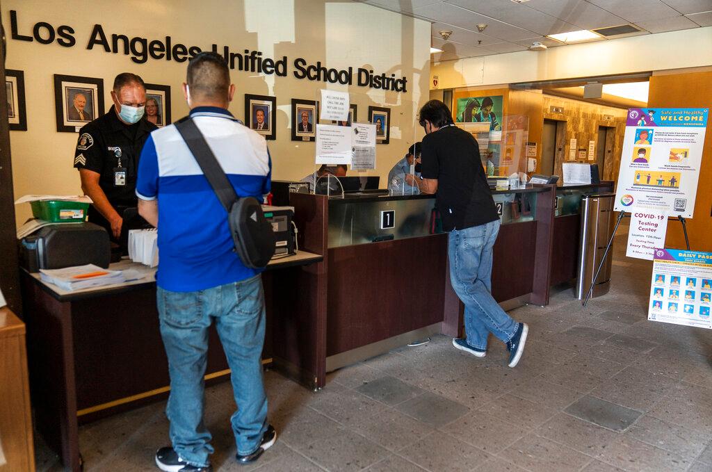 Visitors wait in line to be screened by security before being allowed to enter the Los Angeles Unified School District administrative offices 