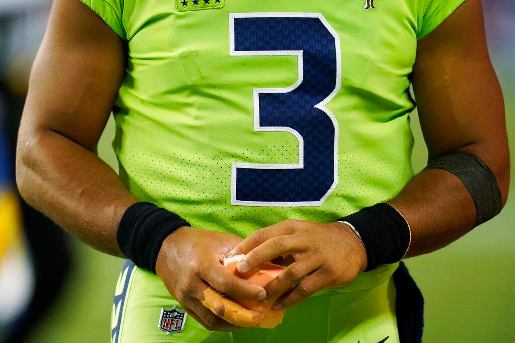 Seattle Seahawks quarterback Russell Wilson holds a sponge near his taped injured finger 