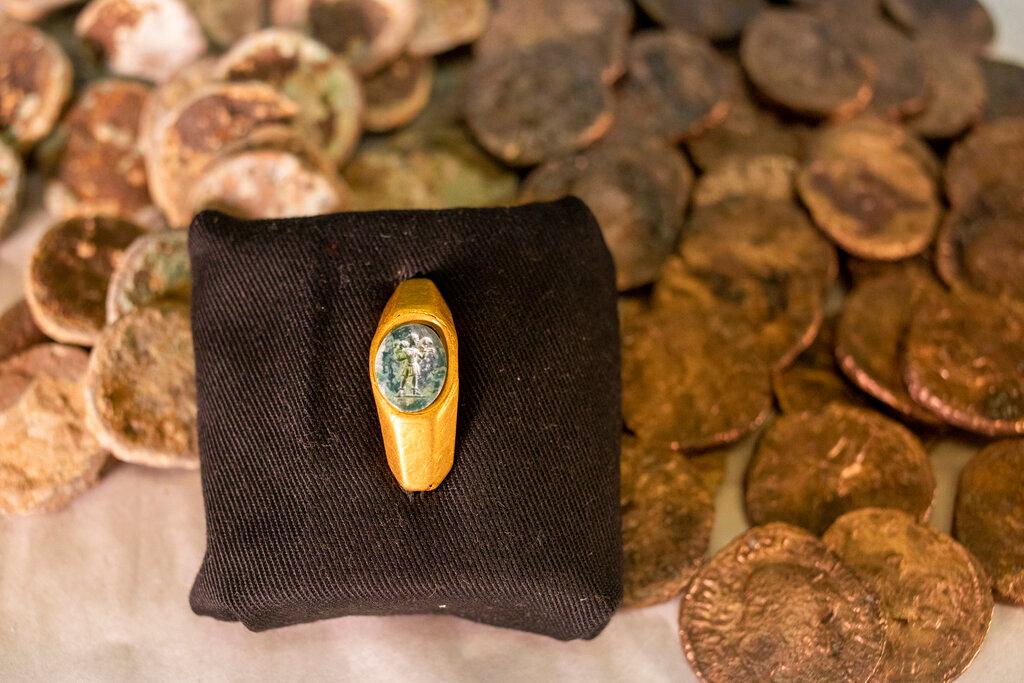 Roman gold ring, its green gemstone carved with the figure of a shepherd carrying a sheep on his shoulders is on display with coins that where found near the ancient city of Caesarea, dated to the Roman and Mamluk periods, around 1,700 and 600 years ago