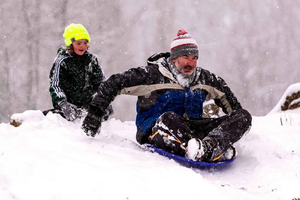 Jones Mckee, 8, gives his father Gabe Mckee a push as the sled at Ritter Park as snow falls in Huntington, W.Va. 