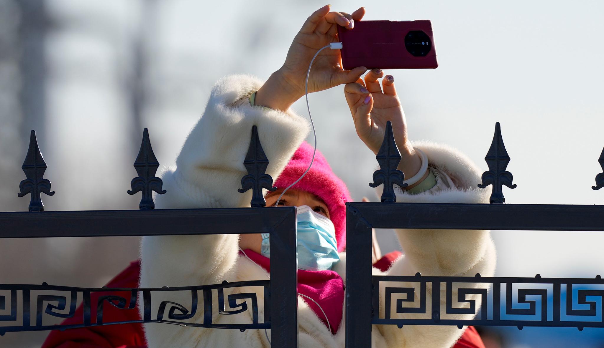 A woman takes a picture of the Olympic Green