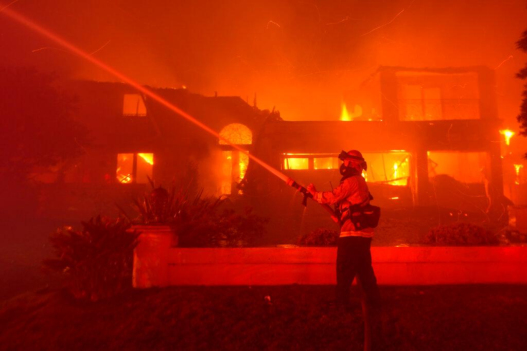 A firefighter works to put out a structure burning during a wildfire Wednesday, May 11, 2022, in Laguna Niguel, Calif