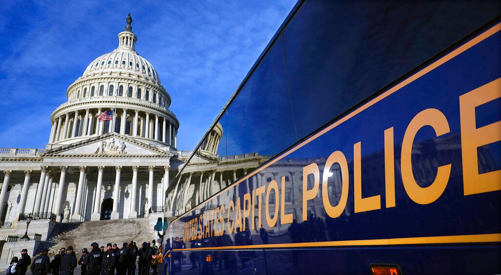 A large group of police arrive on a bus at the Capitol, Thursday, Jan. 6, 2022