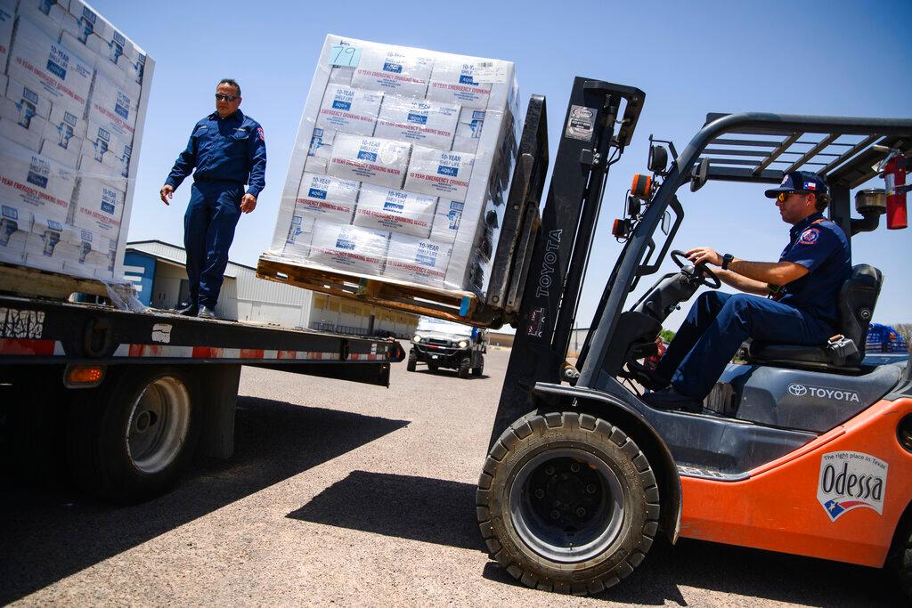 Odessa Fire Rescue Chief John Alvarez, left, and Central Station Captain Austin Yocham unload pallets of emergency drinking water as they help prepare to hand out cases of water for residents