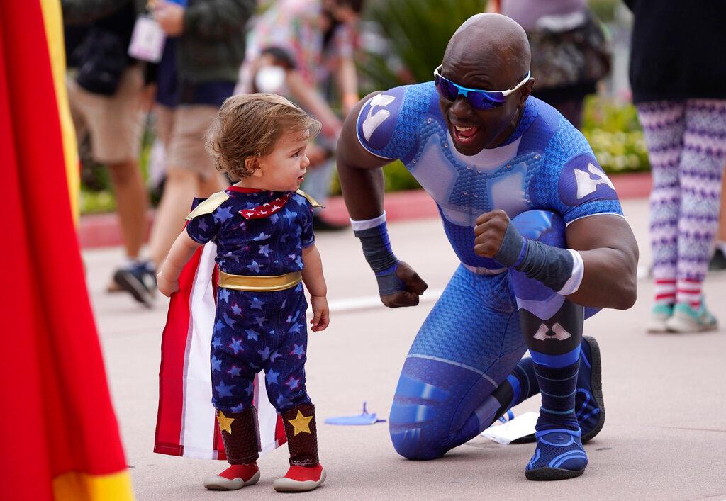 Jay Acey, right, dressed as A-Train from the television series "The Boys," mingles with Maddox Cruz, 1, of Orange, Calif., outside Preview Night at the 2022 Comic-Con International at the San Diego Convention Center