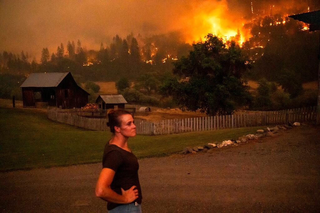 Angela Crawford watches as a wildfire called the McKinney fire burns a hillside above her home in Klamath National Forest, Calif.