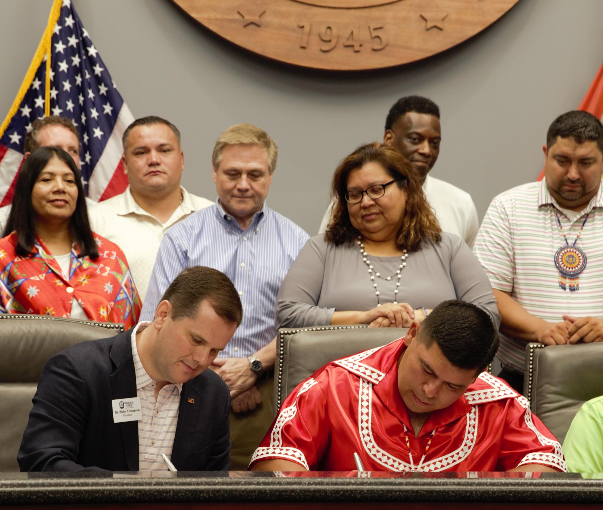 Surrounded by Choctaw Tribal Council members and Mississippi College leaders, Dr. Blake Thompson, front left, MC president, and Chief Cyrus Ben, front right, Mississippi Band of Choctaw Indians tribal chief, sign the memorandum of understanding between MC and the MBCI. 