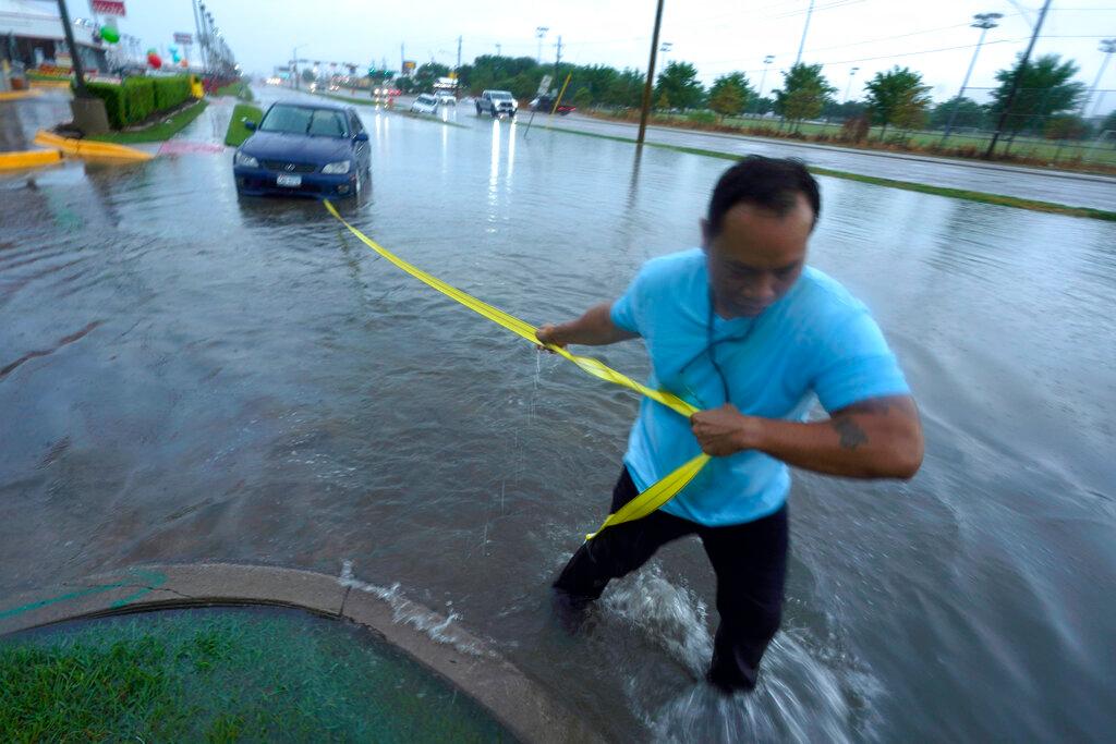 man pulling car from flood waters