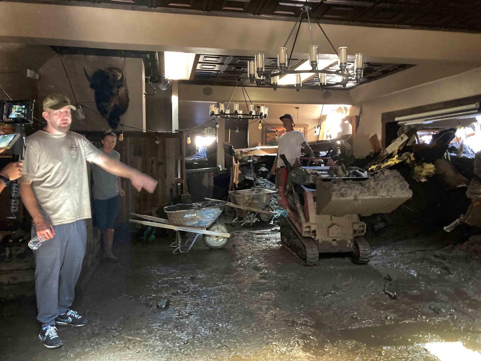 Brandon Gallegos, left, whose family owns the Oak Glen Steakhouse and Saloon, shows the level of the mudslide damage inside the Oak Glen Steakhouse and Saloon in Oak Glen, Calif., on Wednesday, Sept. 14, 2022.