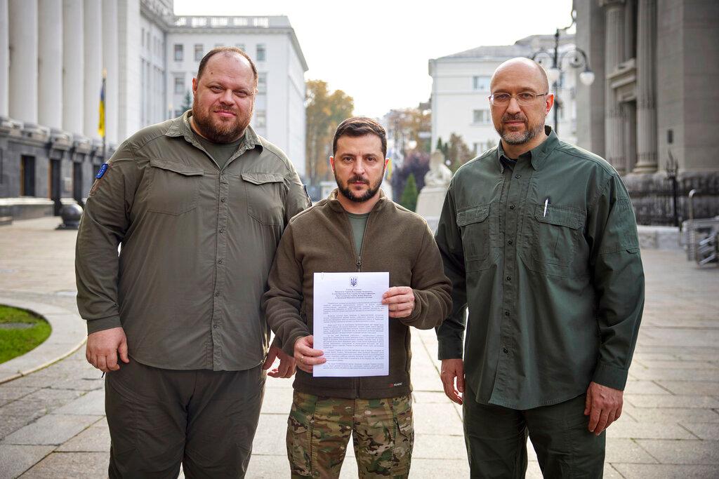 Image of three men one in the middle holding document 