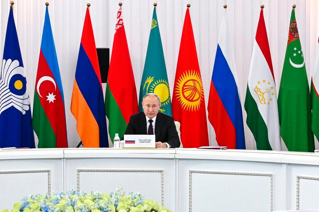 Image of man making speech with flags in background.