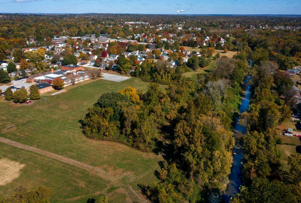 Jana Elementary School, left, which is in the Hazelwood School District, is seen on Monday, Oct. 17, 2022 in Florissant, Mo. Elevated levels of radioactive waste were found at the school, according to a recent report, and the parent-teacher association wants an open public meeting to discuss it. Coldwater Creek, right, which is prone to flooding, was contaminated by waste from nuclear bombs manufactured during World War II.