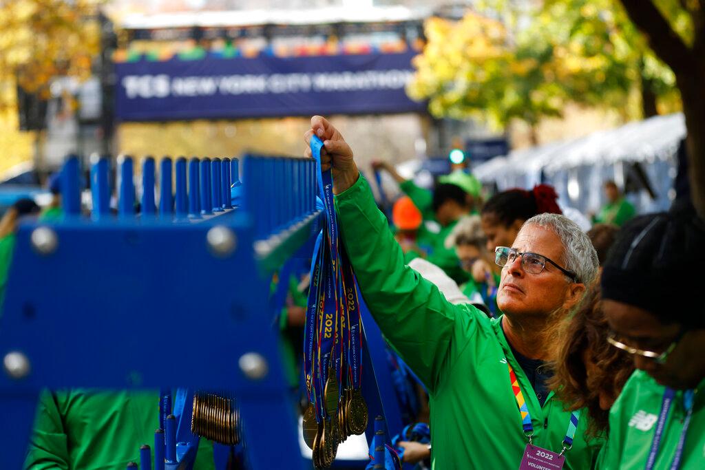 Race volunteers hang finisher medals near the finish line of the New York City Marathon, Sunday, Nov. 6, 2022, in New York.