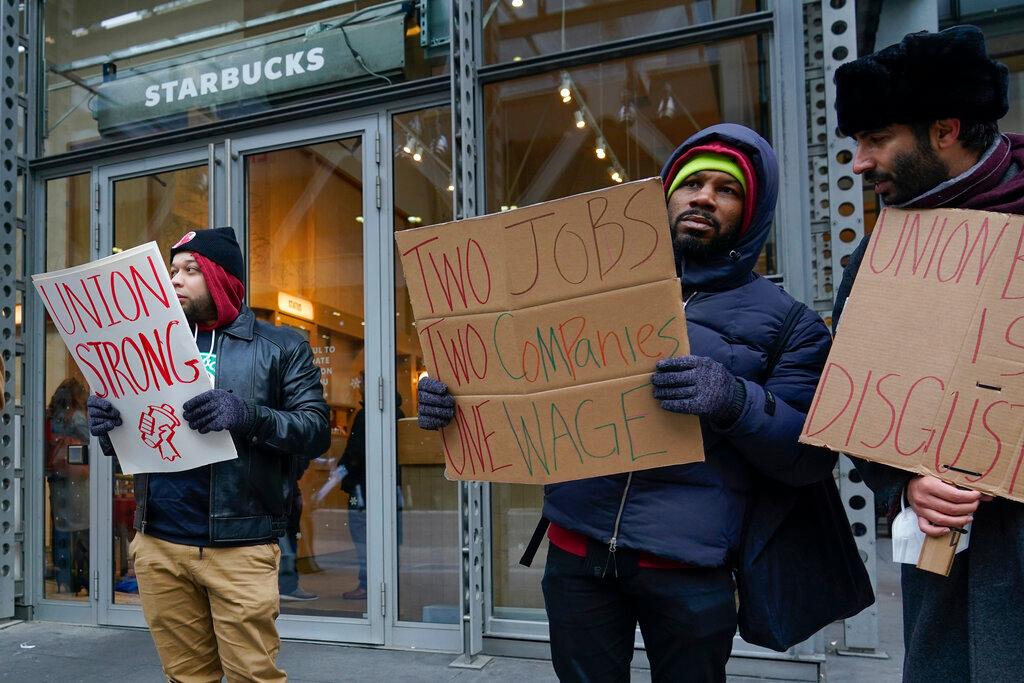 People chant and hold signs in front of a Starbucks in New York