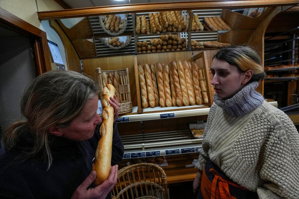 Woman smells a fresh baguette who comes out of the oven