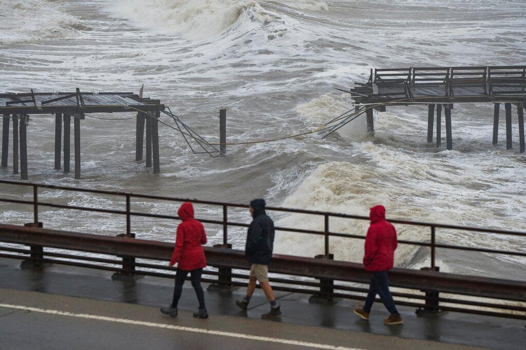 People walk along Cliff Drive to view the Capitola Wharf damaged by heavy storm waves in Capitola, Calif., Thursday, Jan. 5, 2023.