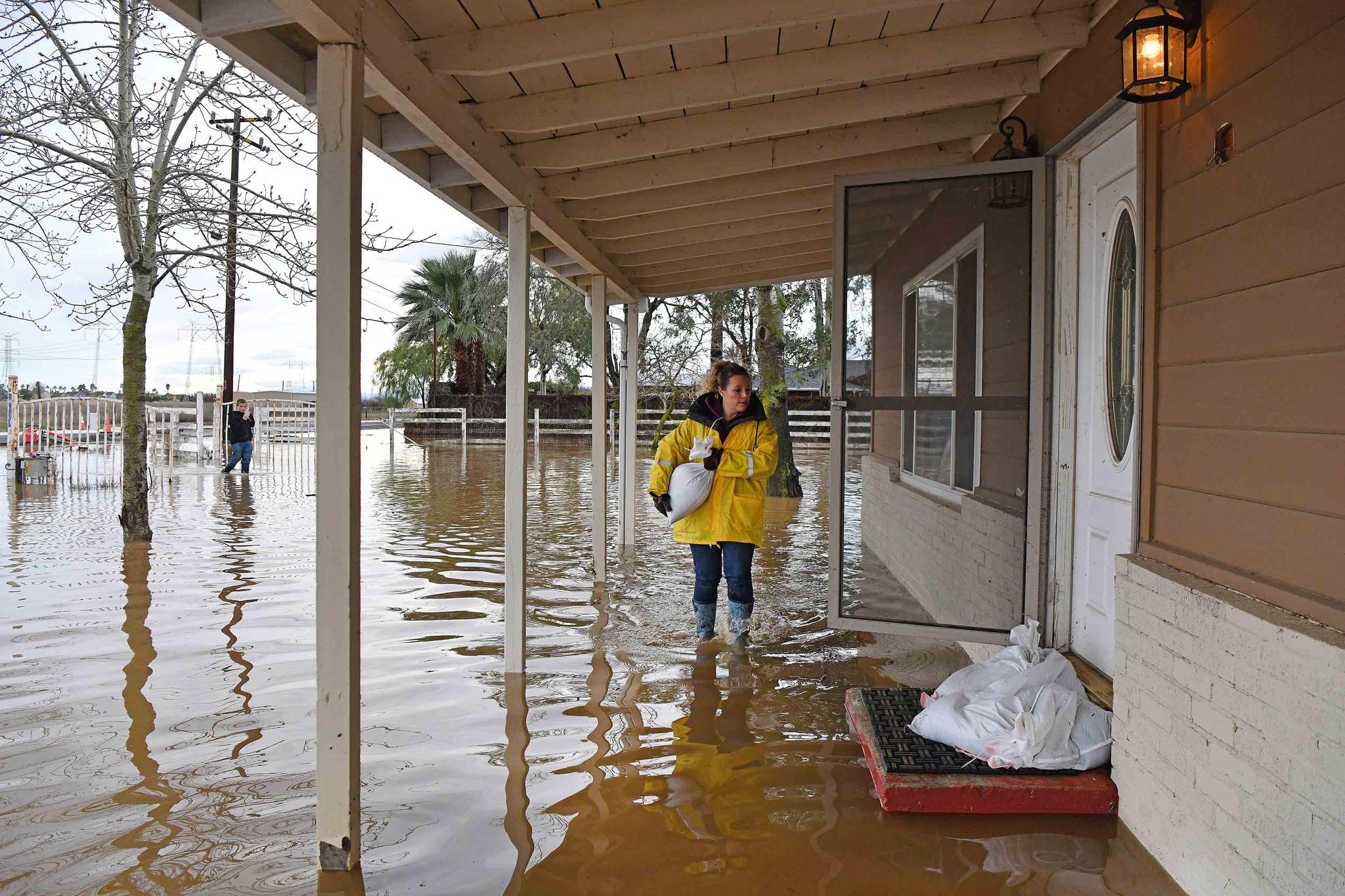 Stephanie Beard, of Brentwood, carries a sand bag to her flooded home on Bixler Road in Brentwood, Calif., on Monday, Jan. 16, 2023.