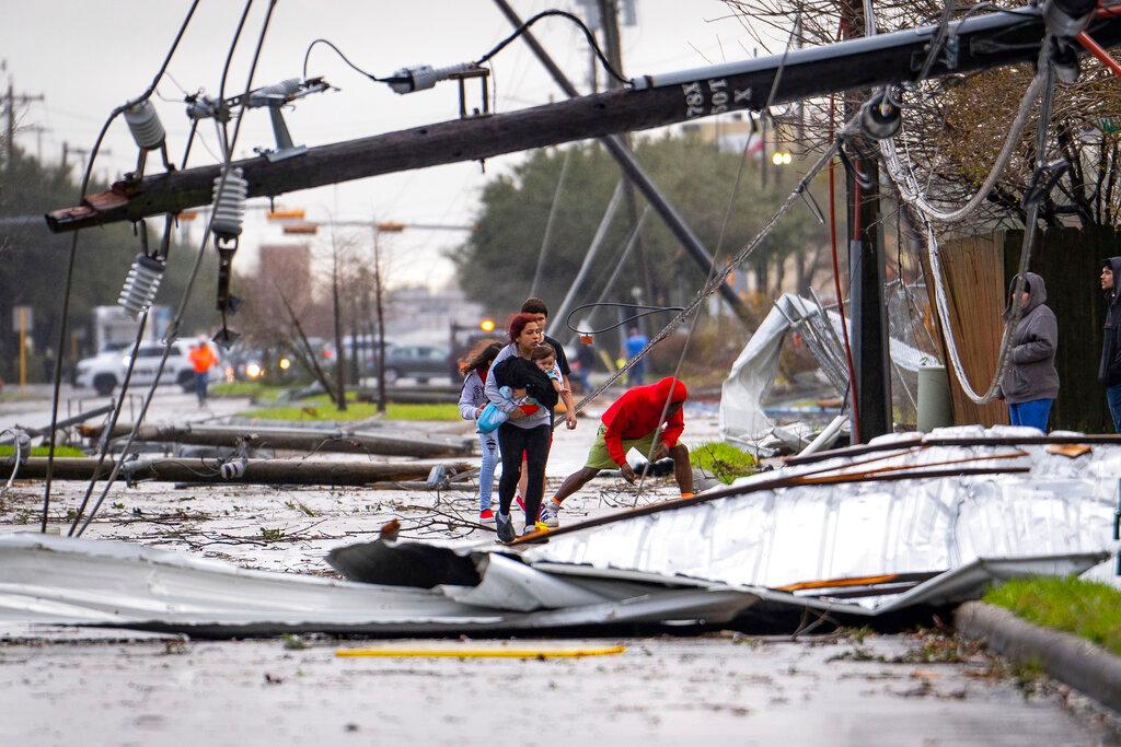 People cross under downed power lines where a tornado was reported in Pasadena, Texas