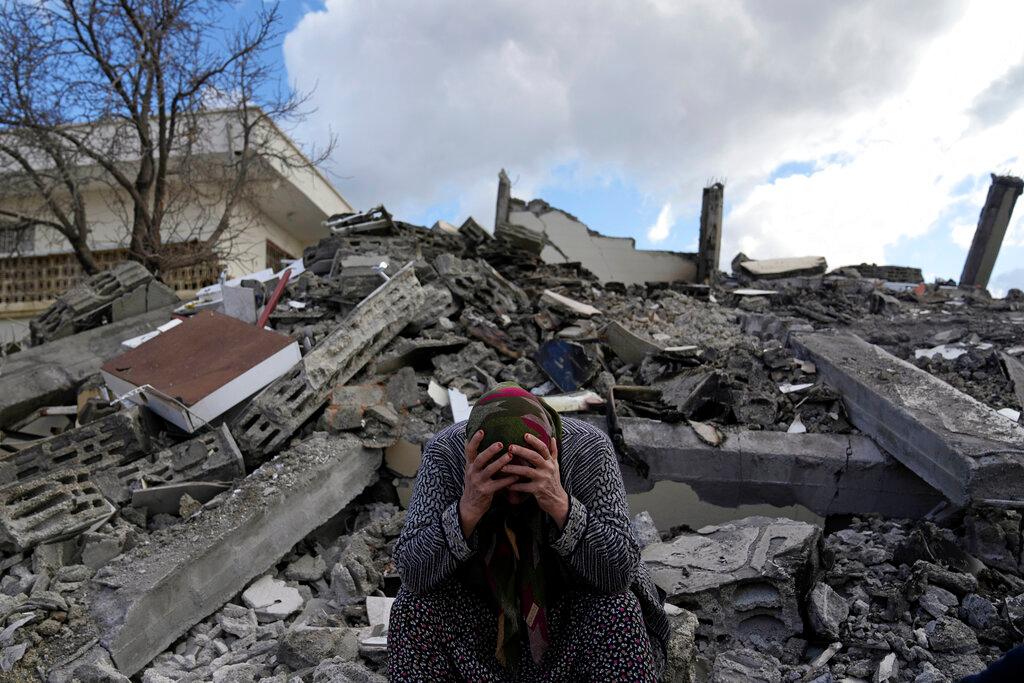 A woman sits on the rubble