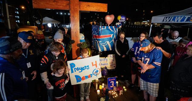 People gathered around a cross, praying for Damar Hamlin.