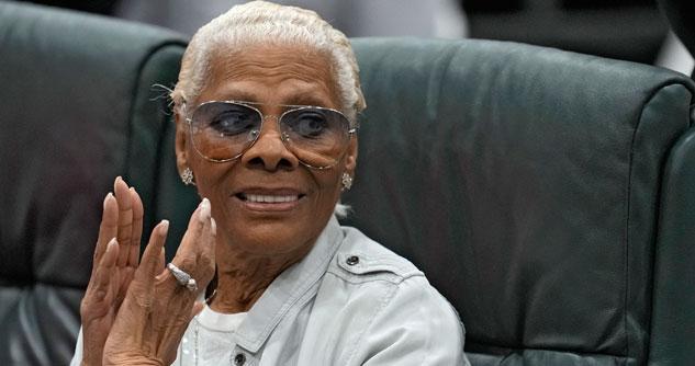 Dionne Warwick, with glasses and gray hair, clapping and smiling