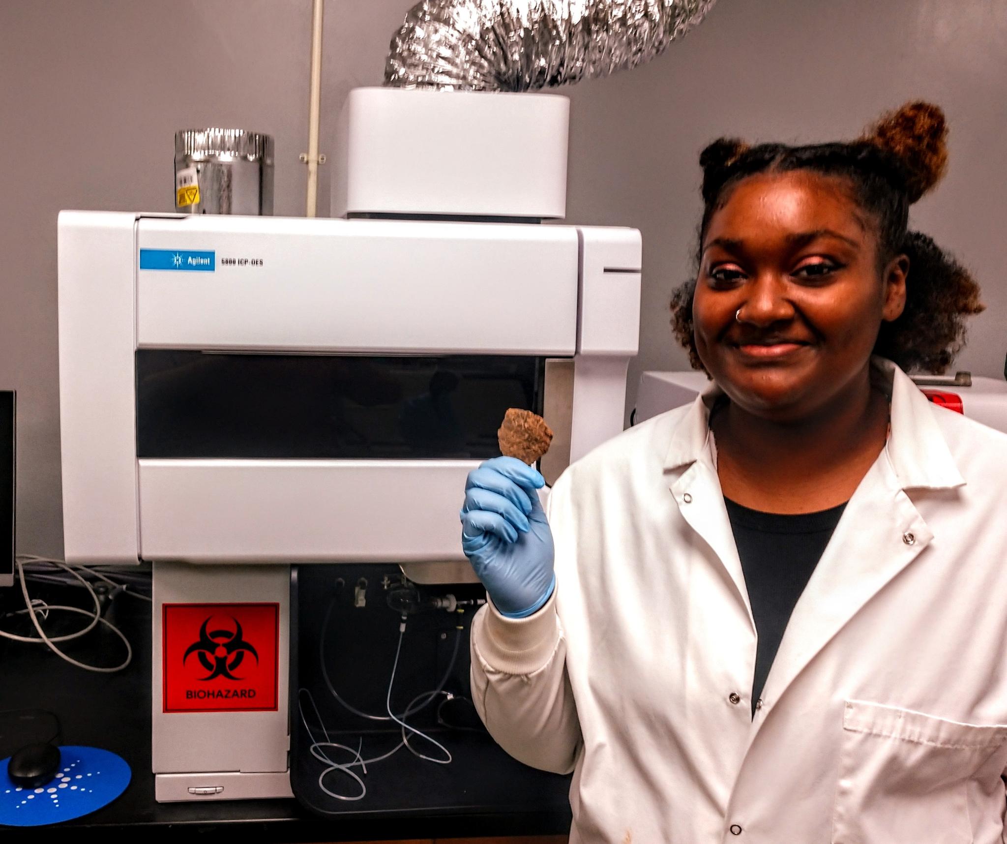 Takaye Farmer, a senior chemistry major from Memphis, holds a pottery shard that will be crushed, prepared, and fed into the state-of-the-art ICP-OES instrument for analysis. 