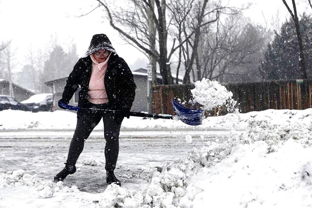 Taja Cantlon clears chunks of snow left by a snowplow from out of her driveway entrance Tuesday afternoon, Feb 14, 2023., in Flagstaff, Ariz.