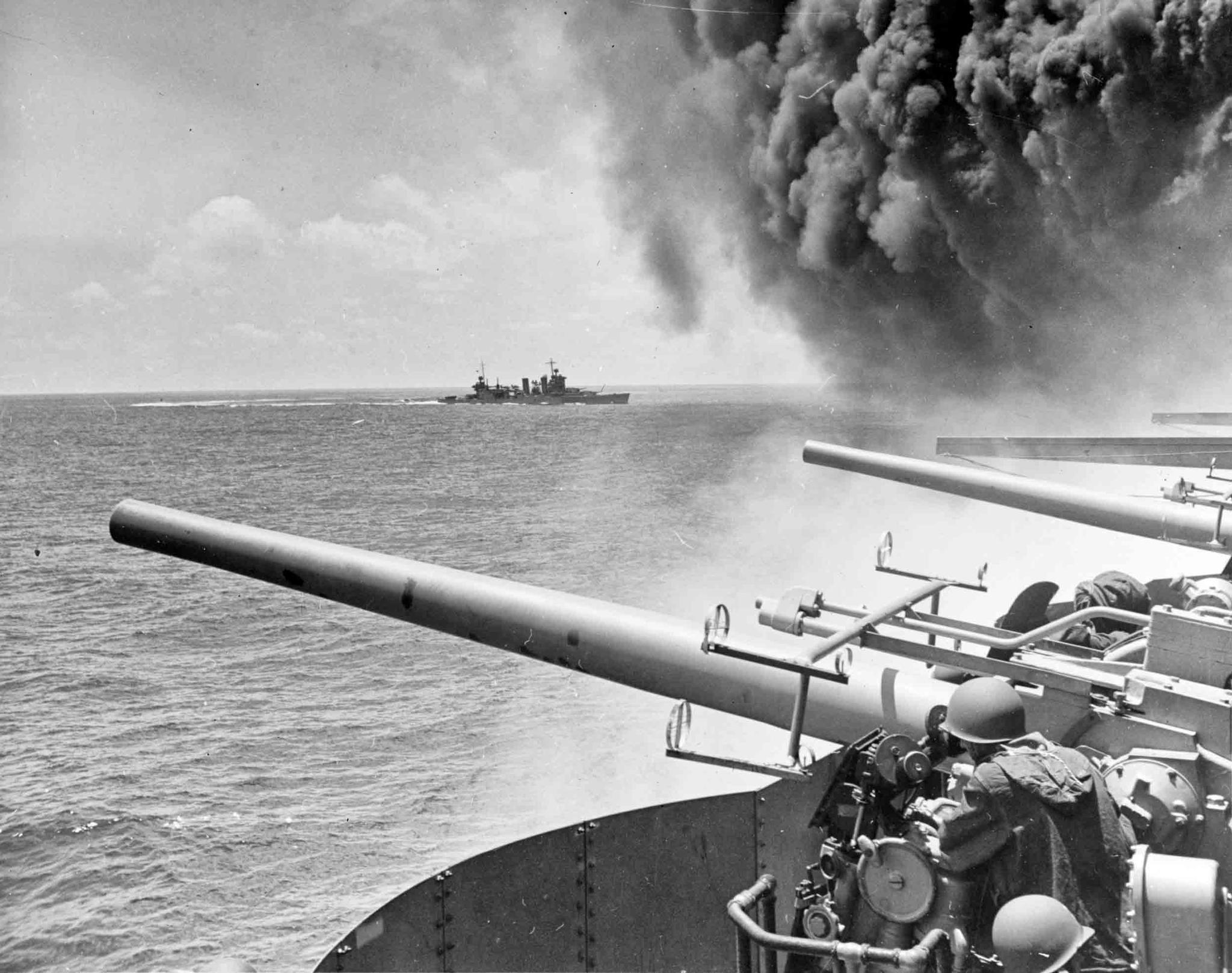 USS Astoria (CA-34) steams by USS Yorktown (CV-5), shortly after the carrier had been hit by three Japanese bombs in the battle of Midway.