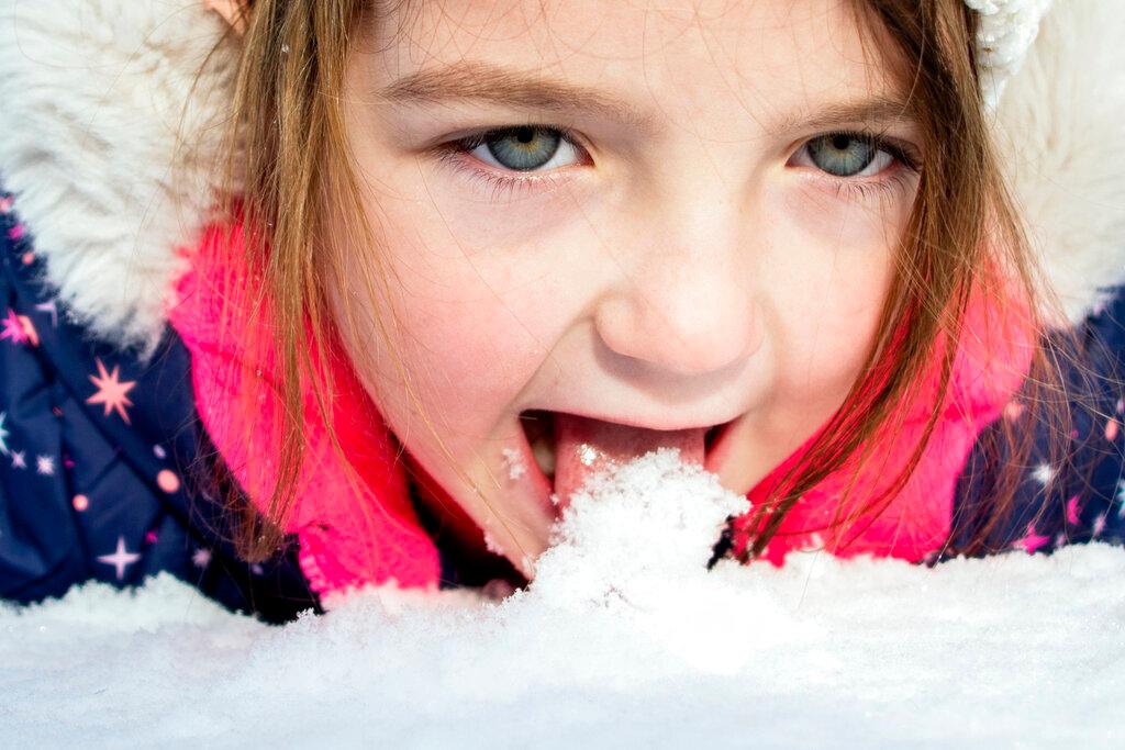 Emma Hart, 5 of Clio, stops to lick up fresh snow as she rolls around while sledding with her father Ryan